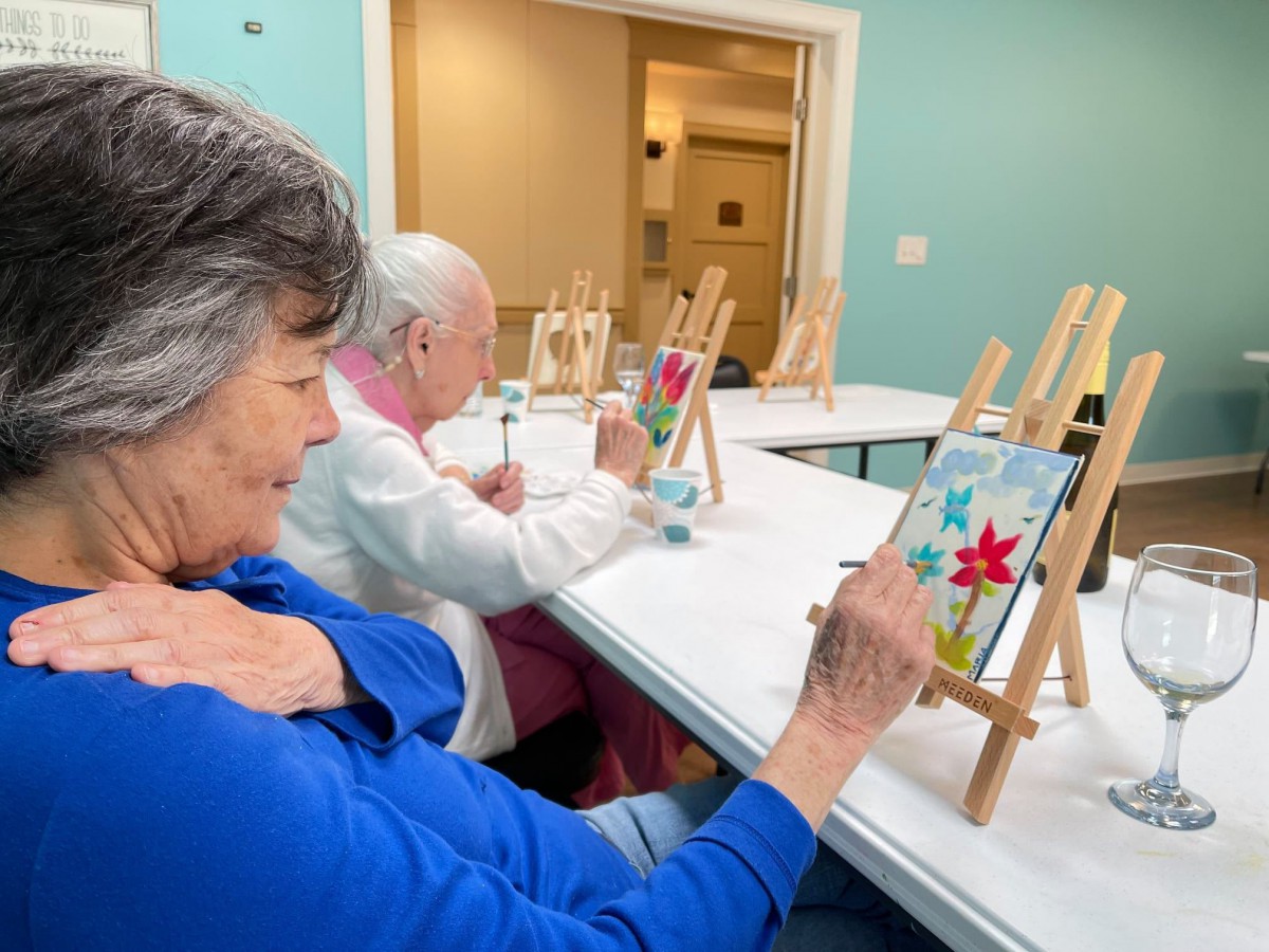 Seniors enjoying a painting class, creating artwork on small easels.
