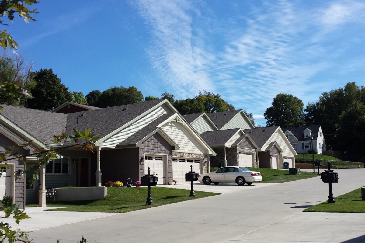 A sunny suburban neighborhood with multiple houses and a clear blue sky.