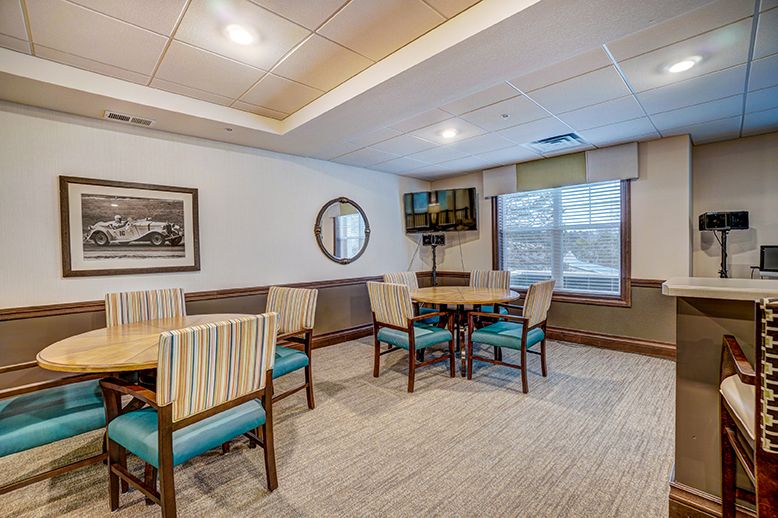 A cozy dining area with tables and chairs, featuring wall art and a large window.