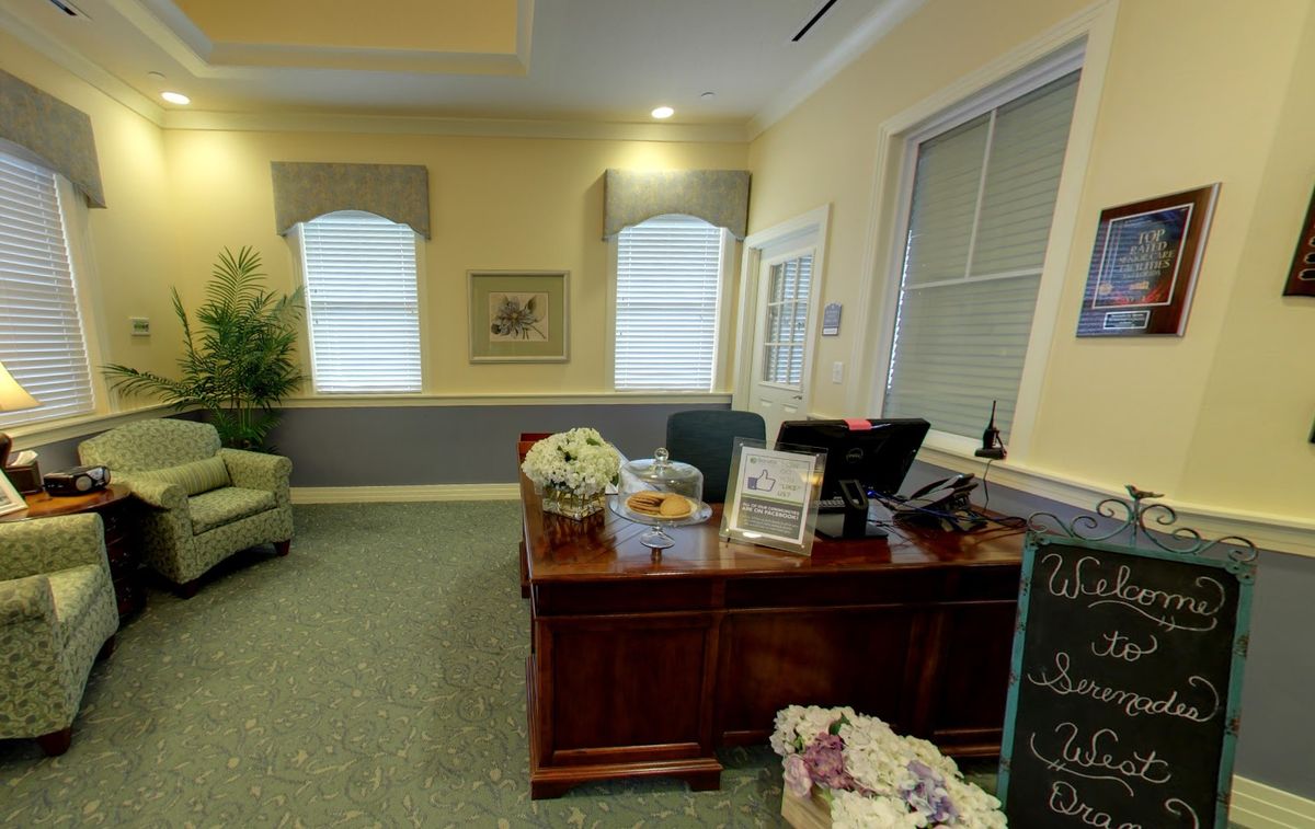 A well-decorated office space with a wooden desk, computer, and natural light from the windows.