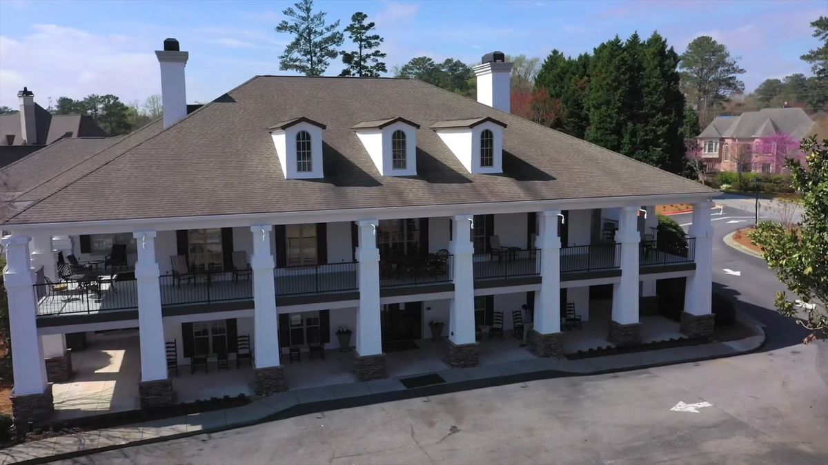 A two-story building with prominent columns and a large roof, featuring balconies on the upper floor.