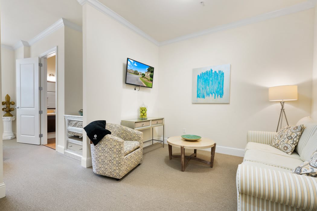 A modern and minimalist living room with neutral tones, featuring comfortable seating, a coffee table, and colorful wall art.