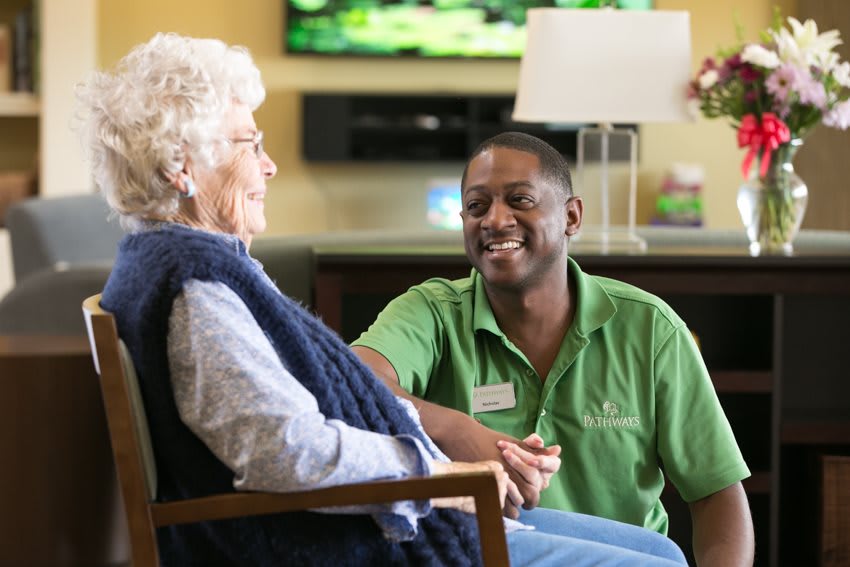 A caregiver happily interacting with an elderly person in a supportive environment.