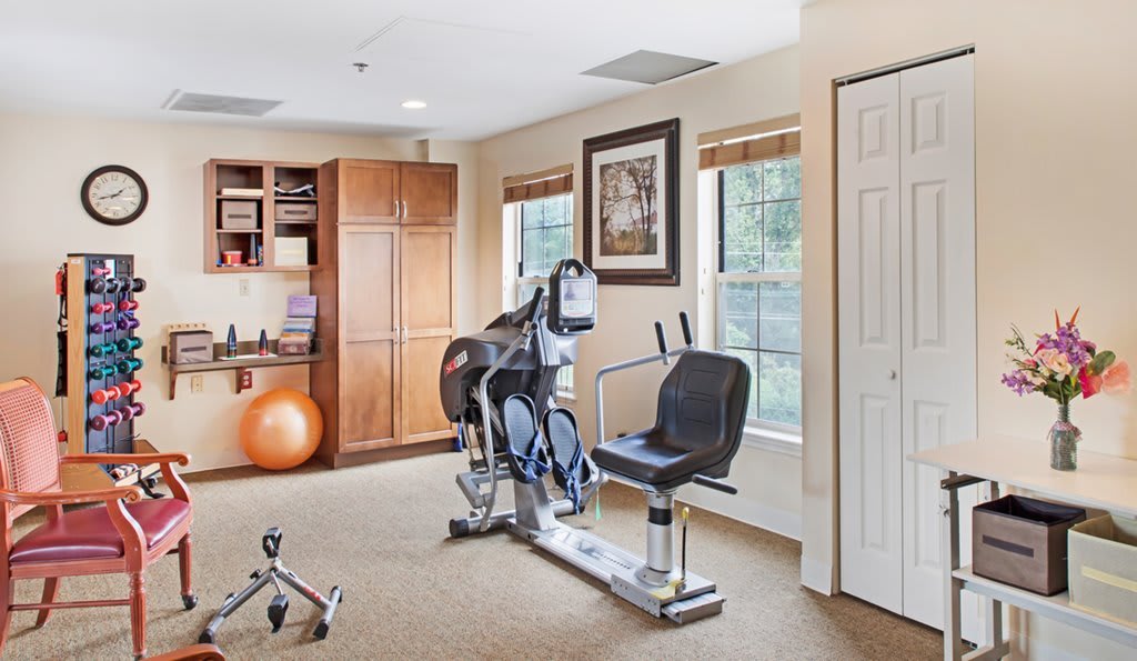 A well-lit home gym featuring a stationary bike and exercise equipment.