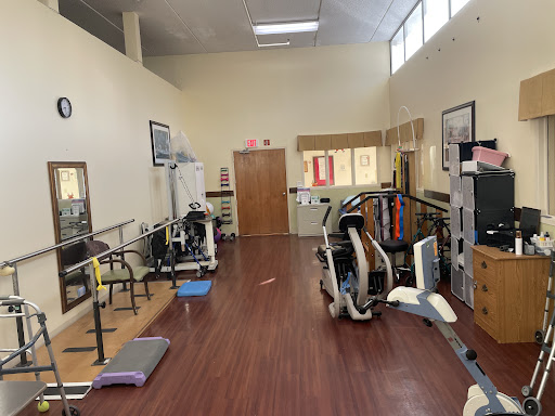 A spacious gym area equipped with various exercise machines and rehabilitation tools.