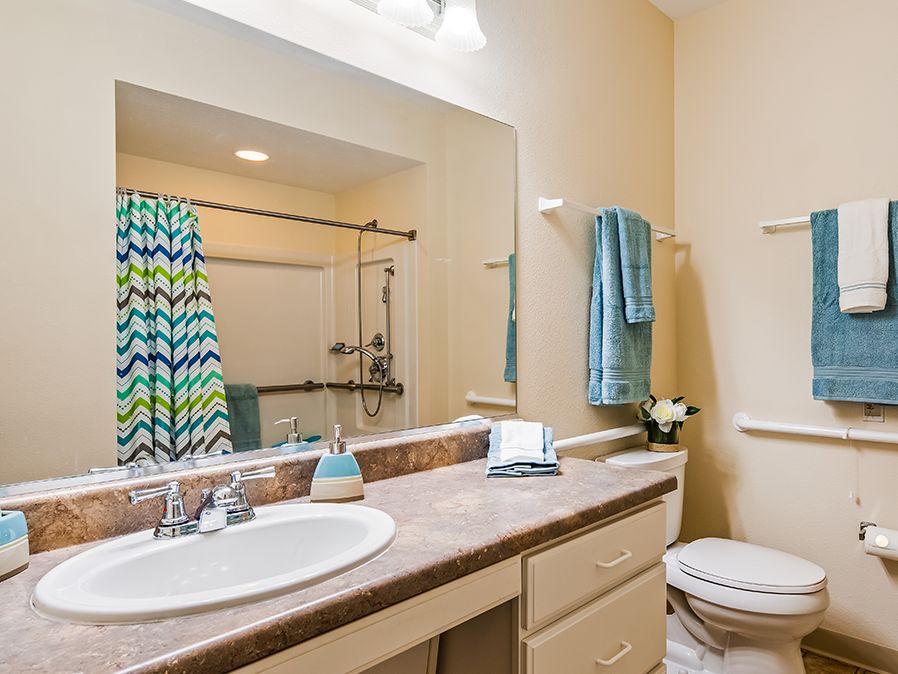 A clean and well-organized bathroom with a sink, mirror, and colorful shower curtain.