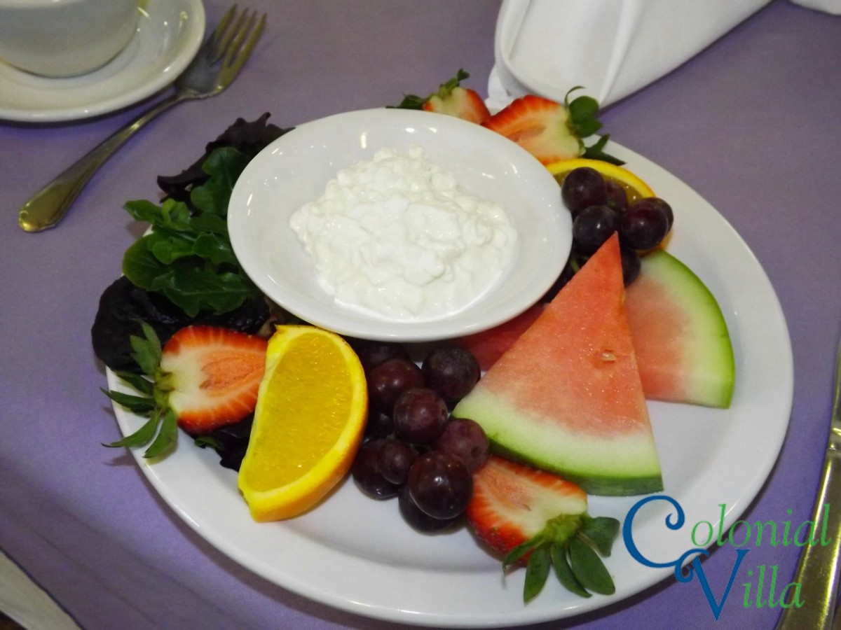 A colorful fruit platter with watermelon, strawberries, grapes, an orange slice, and a bowl of dip.