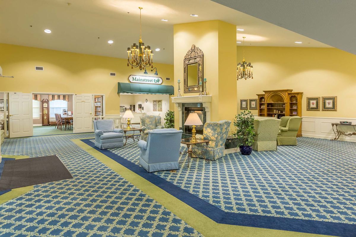 A spacious hotel lobby featuring elegant seating, a chandelier, and a decorative fireplace.