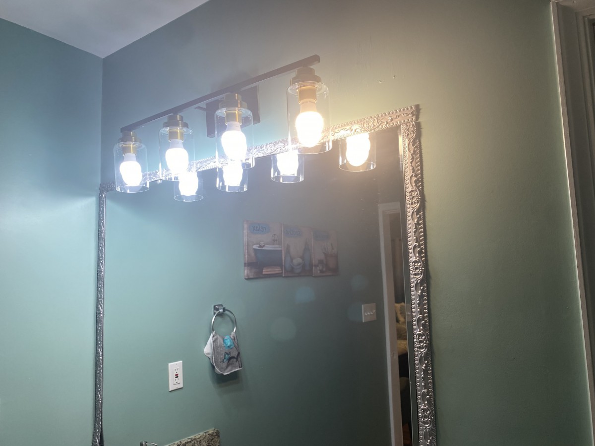 A bathroom mirror with a light fixture overhead illuminating the space.