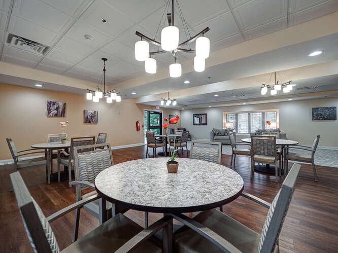A modern dining room with elegant lighting and neatly arranged tables and chairs.