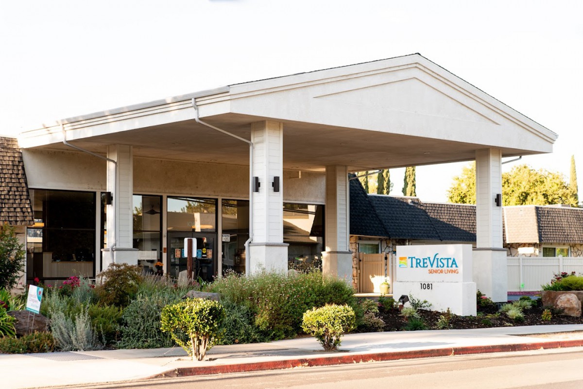 An entrance to a building with a landscaped area and a sign.