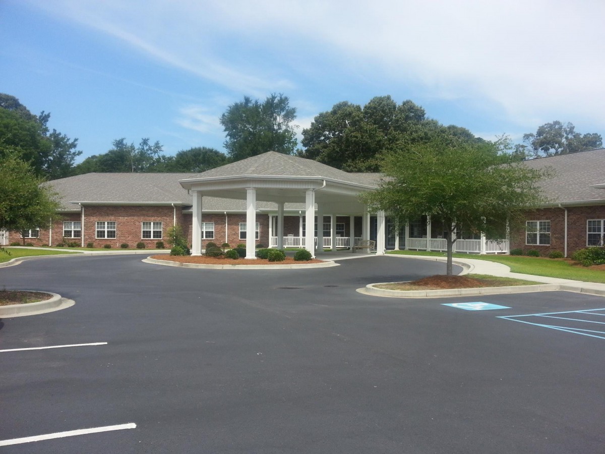 A medical facility with a circular driveway and surrounding trees.