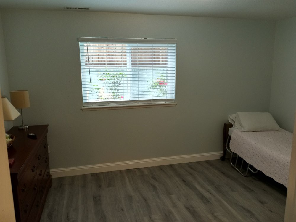 A minimalist bedroom with a bed and a window featuring wooden flooring.