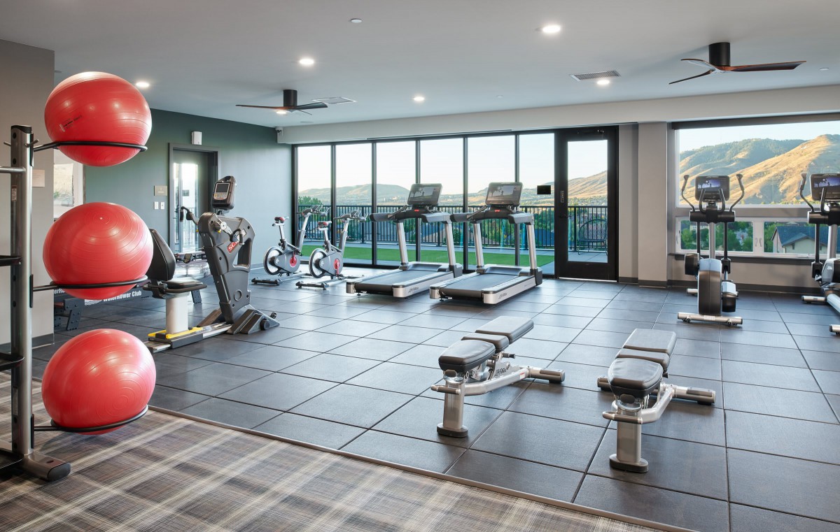 A modern gym with various exercise equipment including treadmills, stationary bikes, and weights.