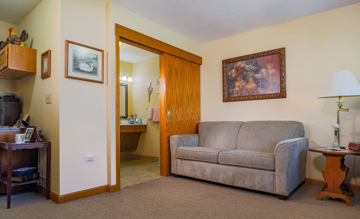 A cozy living room with a sofa and artwork, opening into a bathroom.