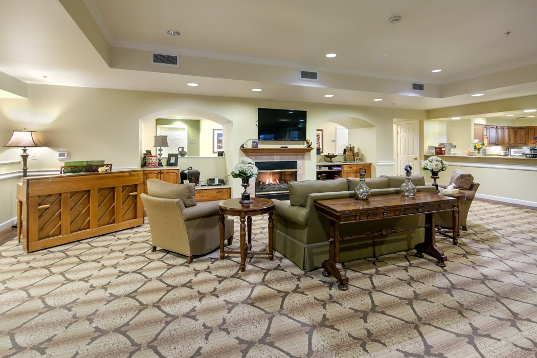 A modern living room with comfortable seating and a central television above a fireplace.