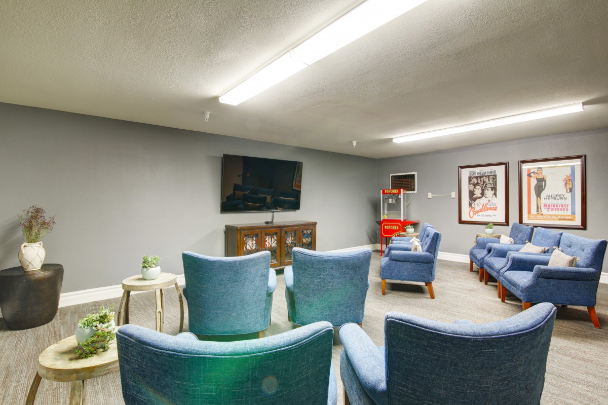 A modern living room with multiple chairs arranged facing a wall-mounted television.