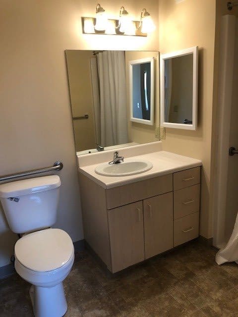 A clean and simple bathroom with a sink, mirror, and toilet.