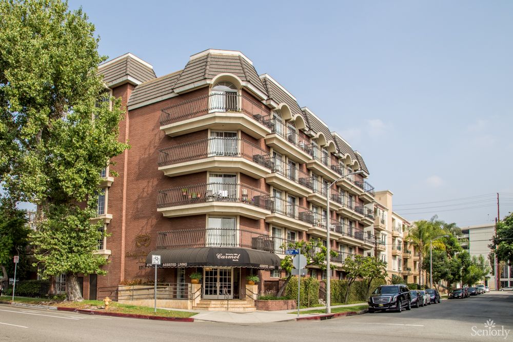 A multi-story residential building on a street corner with balconies and brick facade.
