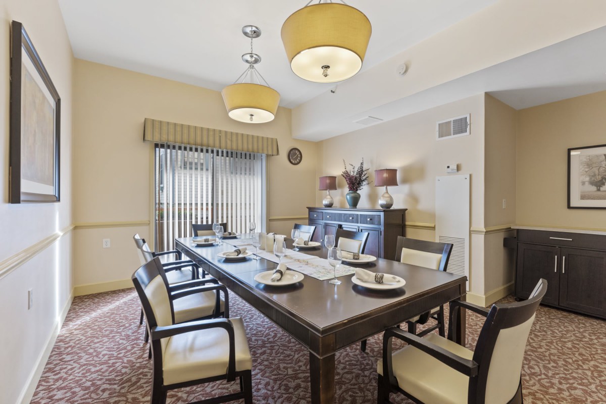 A sophisticated dining room with a long table and elegant chairs, featuring tasteful lighting and decor.
