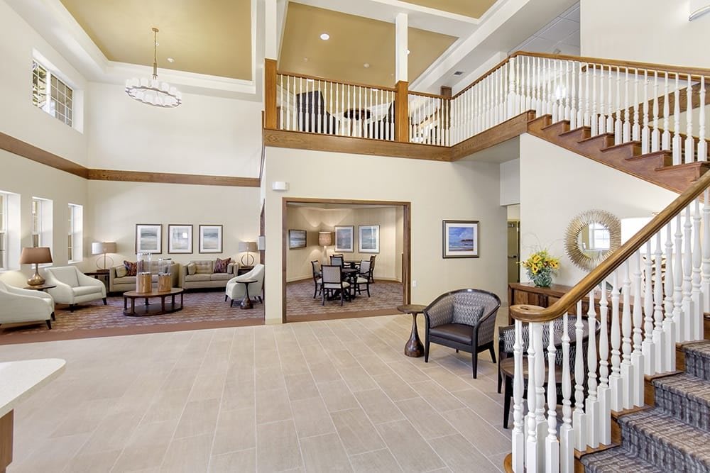 A spacious lobby with seating areas, artwork, and a staircase leading to an upper level.