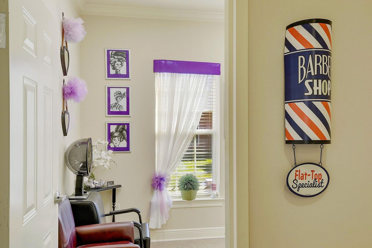 A cozy barbershop interior with purple accents, featuring a salon chair and decorative wall art.