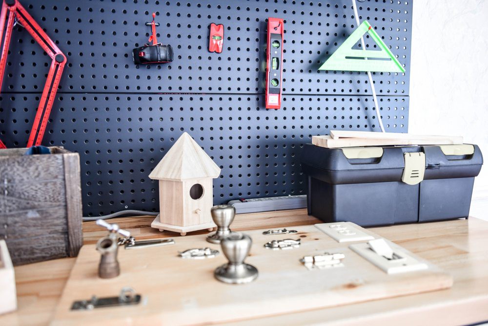 A well-organized workshop with tools hanging on a pegboard and a birdhouse in progress.
