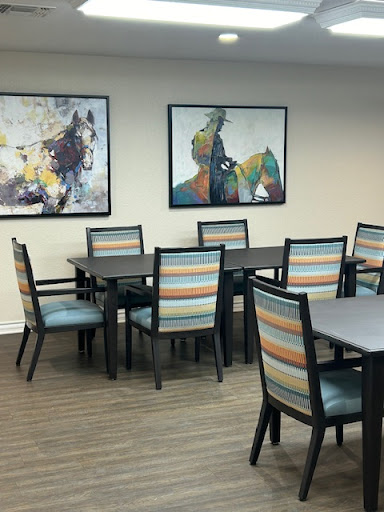 A modern dining room setup featuring wooden tables and striped chairs, complemented by colorful artwork on the walls.