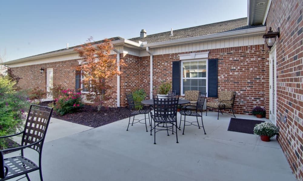 A cozy outdoor patio area with a table and chairs set against a brick house exterior.