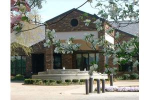 A picturesque view of a building with a fountain surrounded by trees.