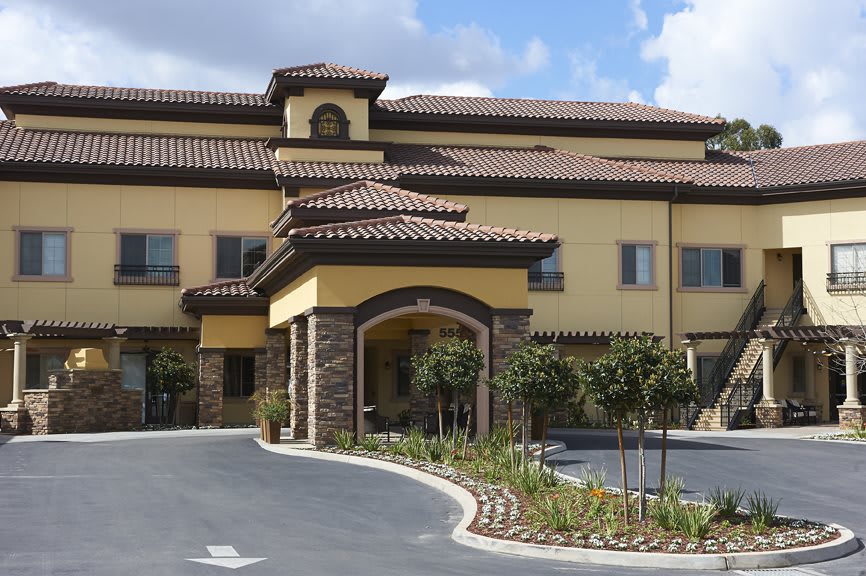 A Mediterranean-style building with a landscaped entrance and tiled roof.