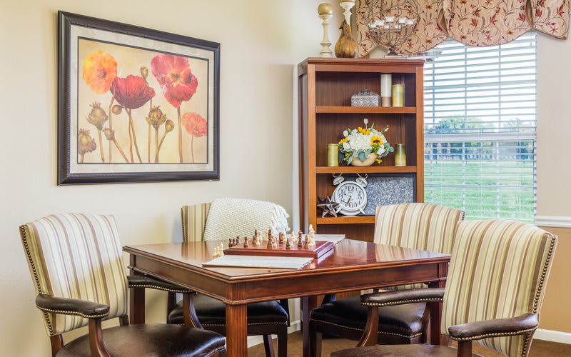 A cozy dining room with a chessboard on the table and artwork on the wall.