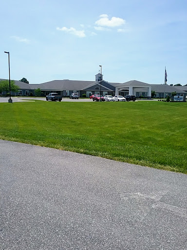 A view of a building surrounded by grassy areas and parked vehicles under a clear sky.