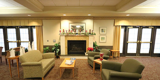 A cozy living room with green sofas and a festive fireplace decorated for the holiday season.