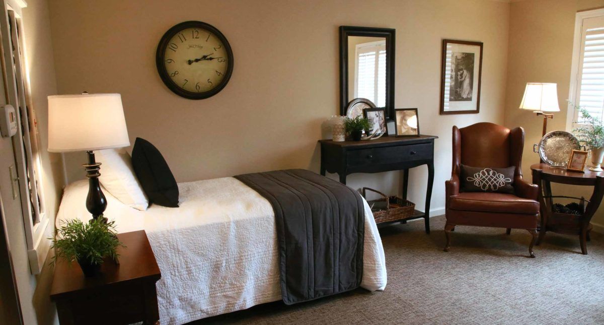 A cozy bedroom with a single bed, decorative clock, and mirror.