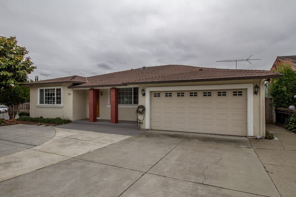 A suburban house with a large garage and driveway under a cloudy sky.