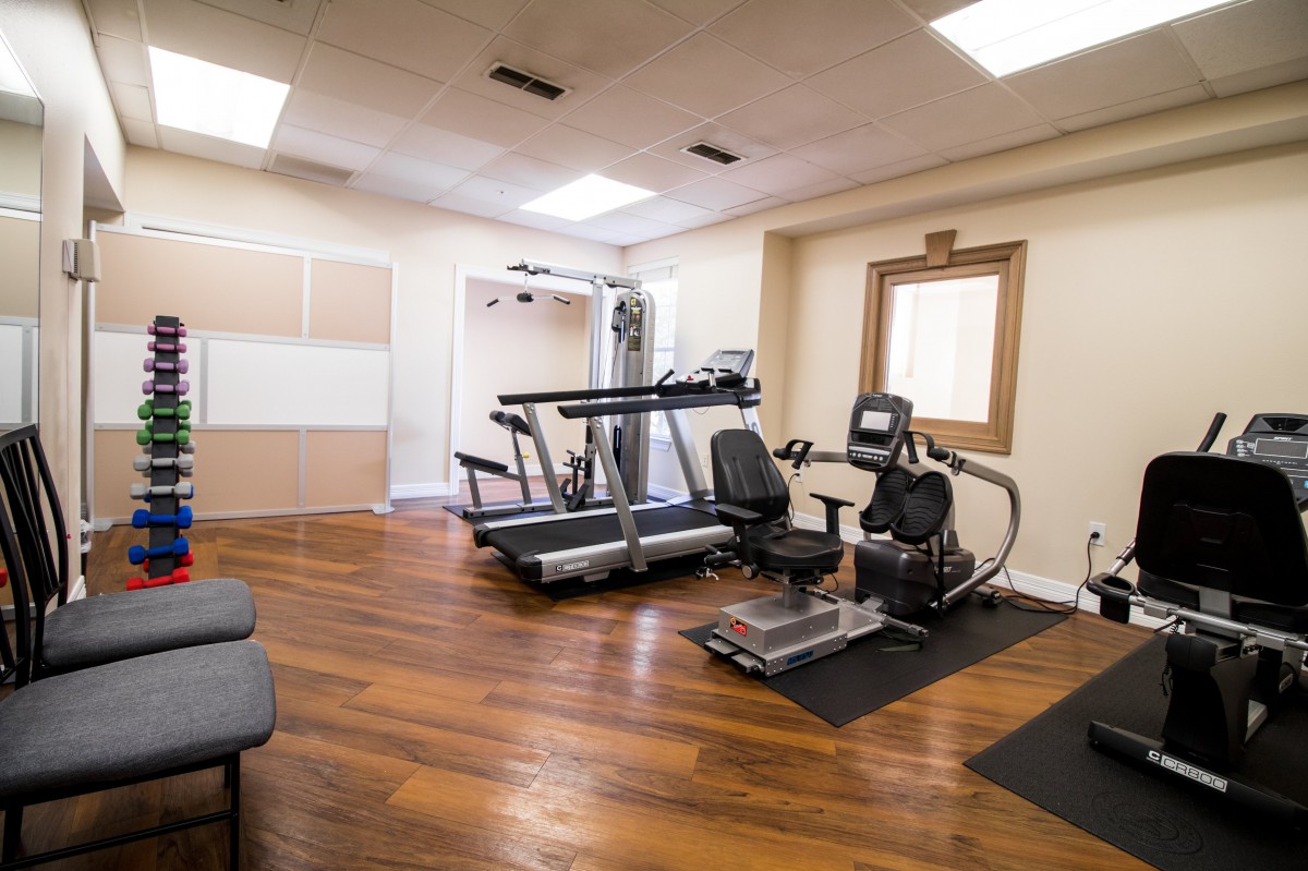 A small home gym with exercise equipment, including a treadmill and recumbent bike.