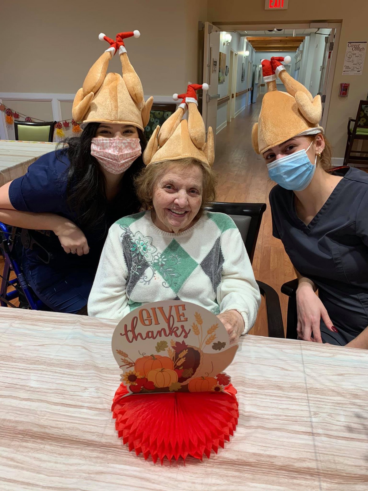 Three people wearing turkey hats celebrate Thanksgiving together.