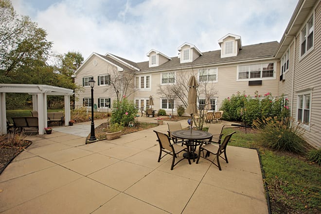 A residential building with an outdoor patio featuring a table and chairs.