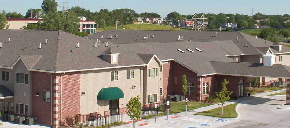 A suburban residential building with a green awning and surrounding greenery.