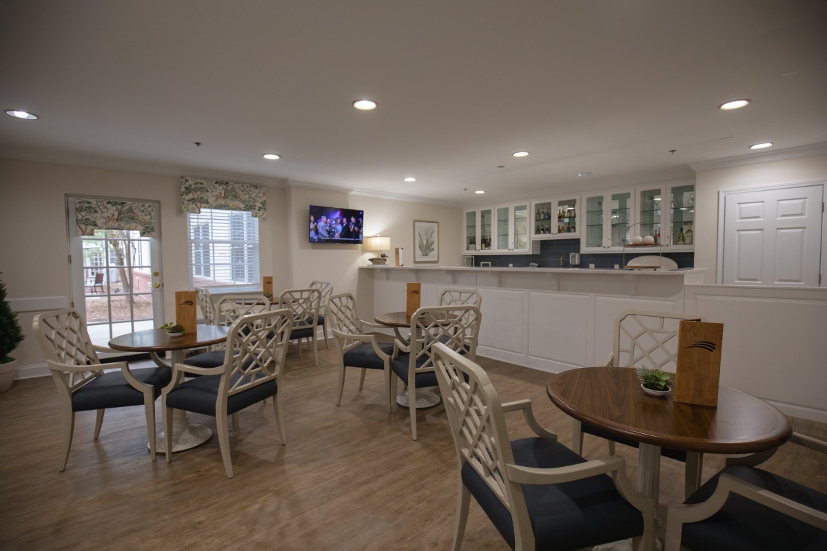 A cozy dining area with tables, chairs, and a kitchenette.