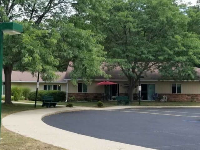 A building surrounded by trees with a paved walkway in the foreground.