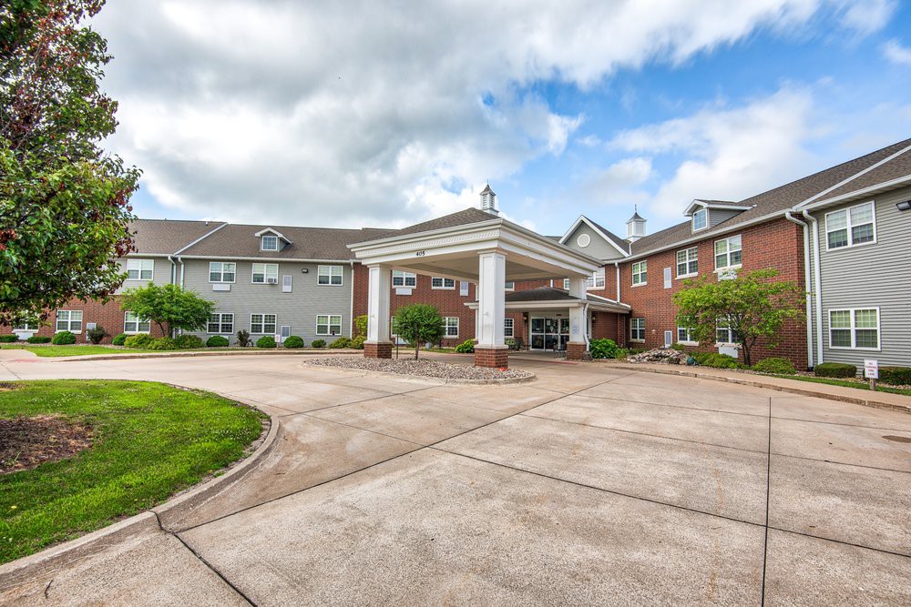 A residential building with a grand entrance featuring columns and a spacious driveway.