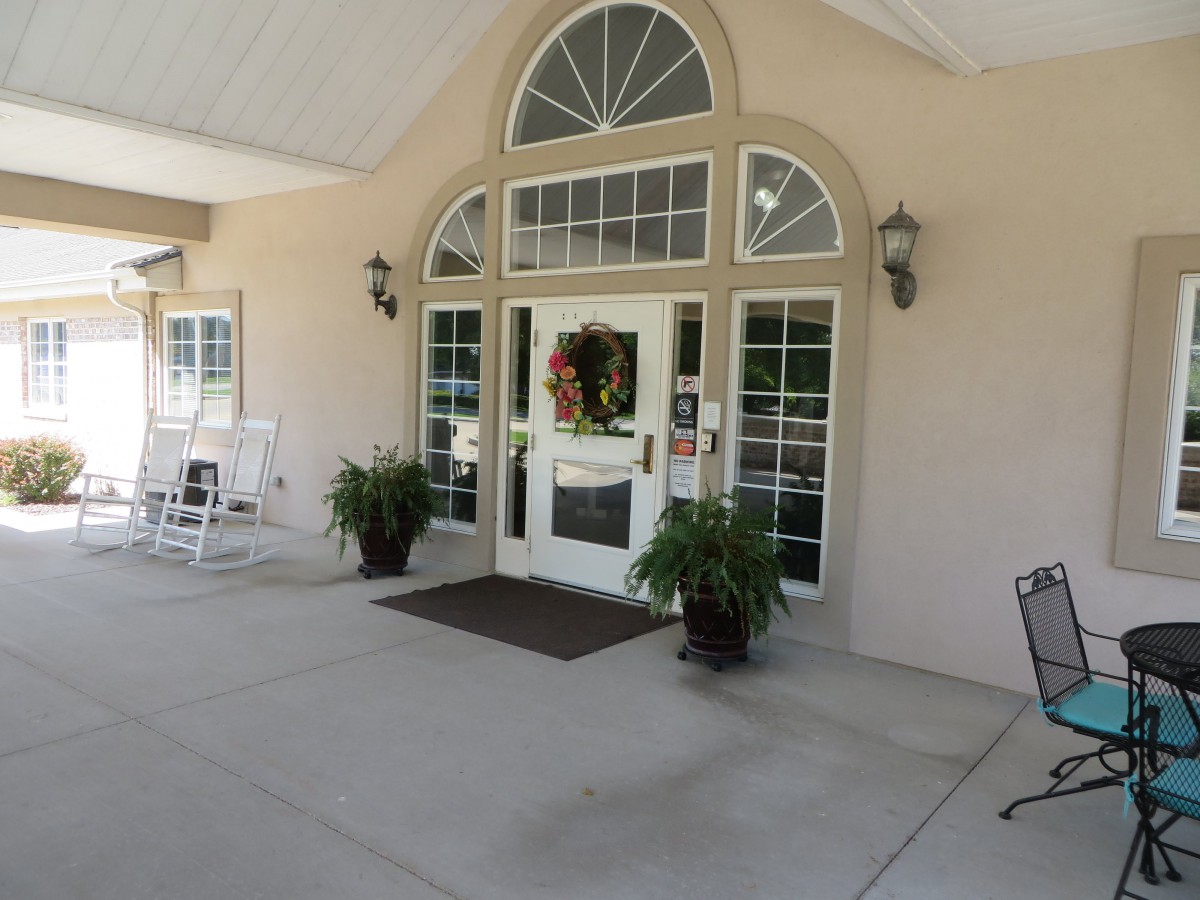 A welcoming building entrance with a decorated door and potted plants.