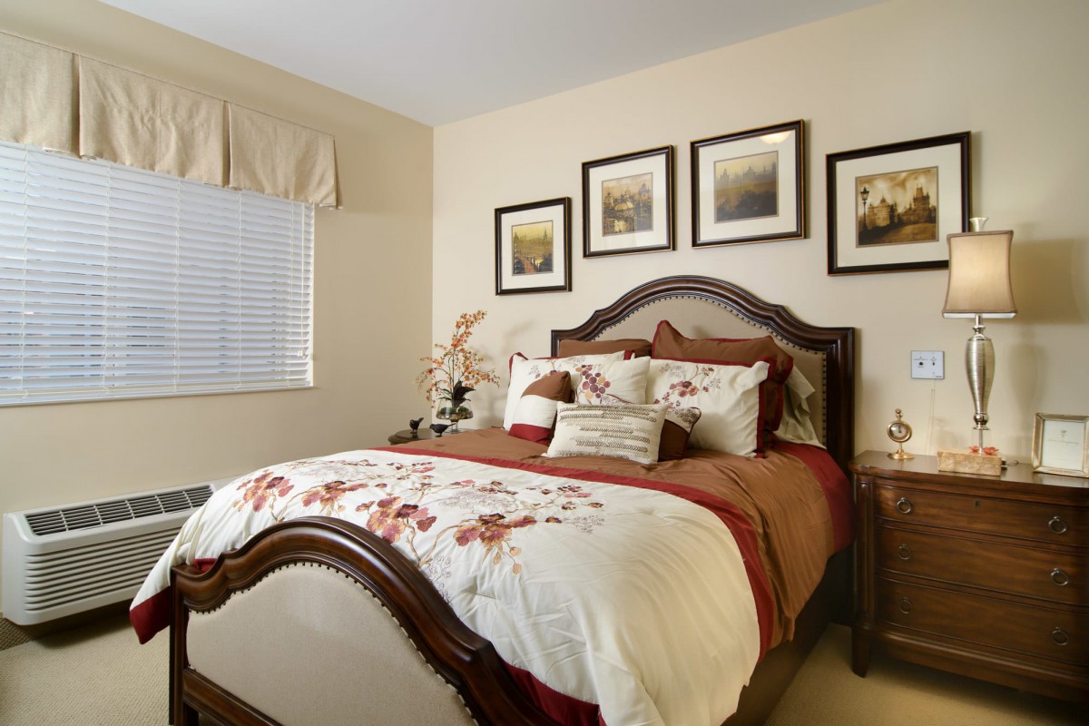 A cozy and elegantly decorated bedroom with a wooden bed frame, floral bedding, and framed artwork on the wall.