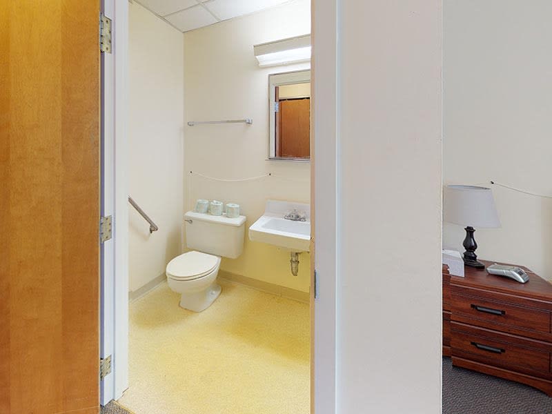 A view of a clean and simple bathroom with a toilet, sink, and mirror.