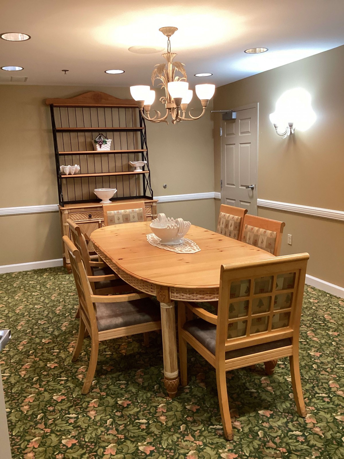 A cozy dining room with a wooden table and chairs, illuminated by a chandelier.