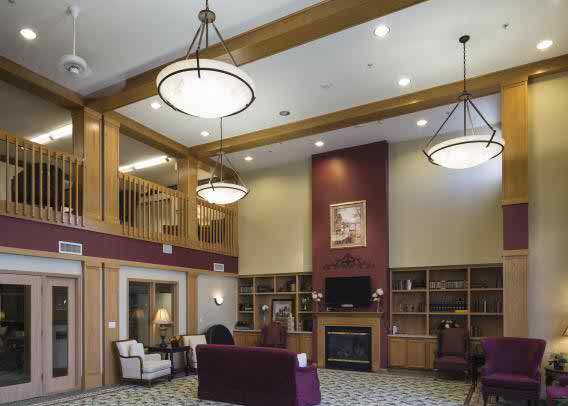 A cozy lobby area with high ceilings, featuring elegant lighting and wooden beams.