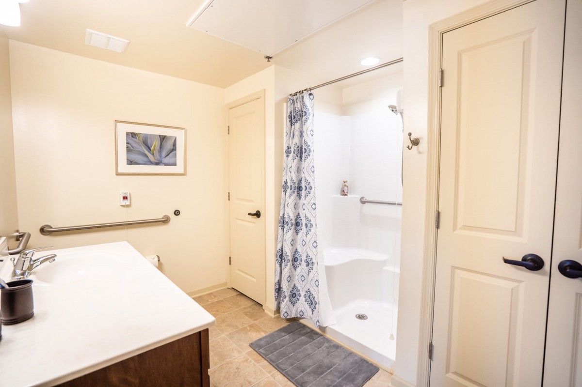 A modern bathroom with a shower featuring a patterned curtain and tile flooring.