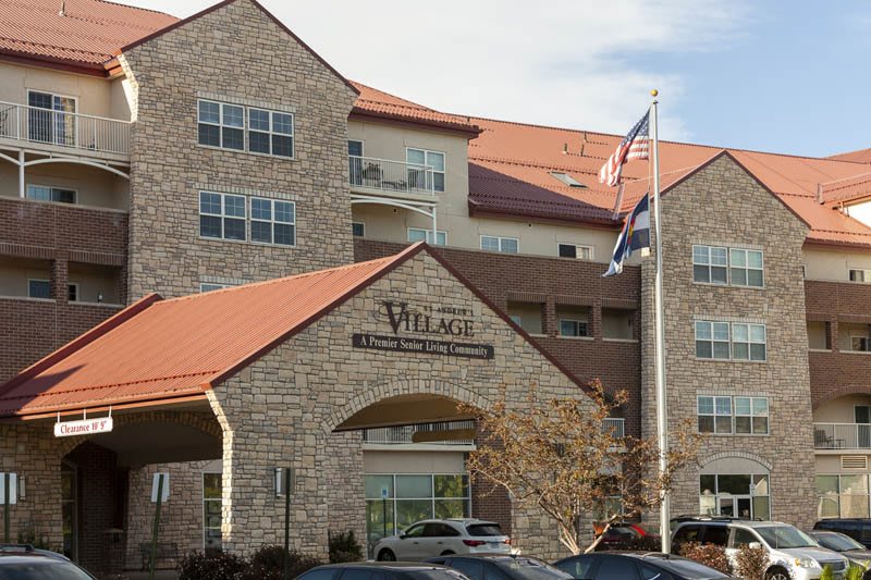 The entrance of a stone facade building with flags, likely a retirement home.
